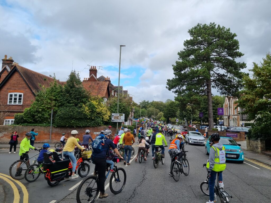 Photo of many children and adults cycling along the road in Guildford. There is a mass of cyclists going up the hill as far as the eye can see.